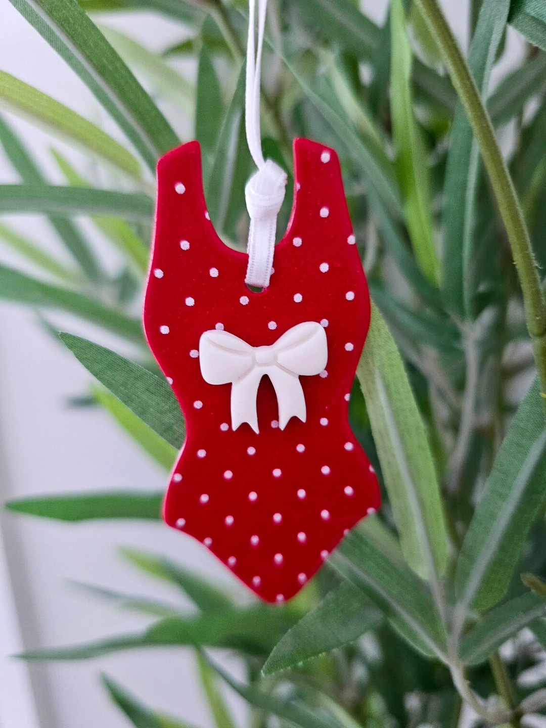 Red polka dot swimsuit decoration with bow, hanging on tree – fun festive gift or stocking filler for swimmers.