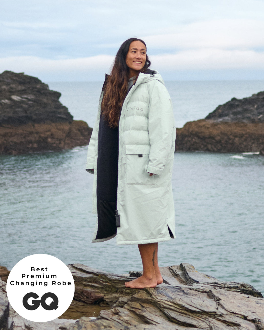 Lead_women - Woman wearing a Vivida Lifestyle All Weather Puffer Changing Robe, Matcha Green Drying Robe for swimming standing in snow. Sticker: Best Premium Changing Robe - The Independent.