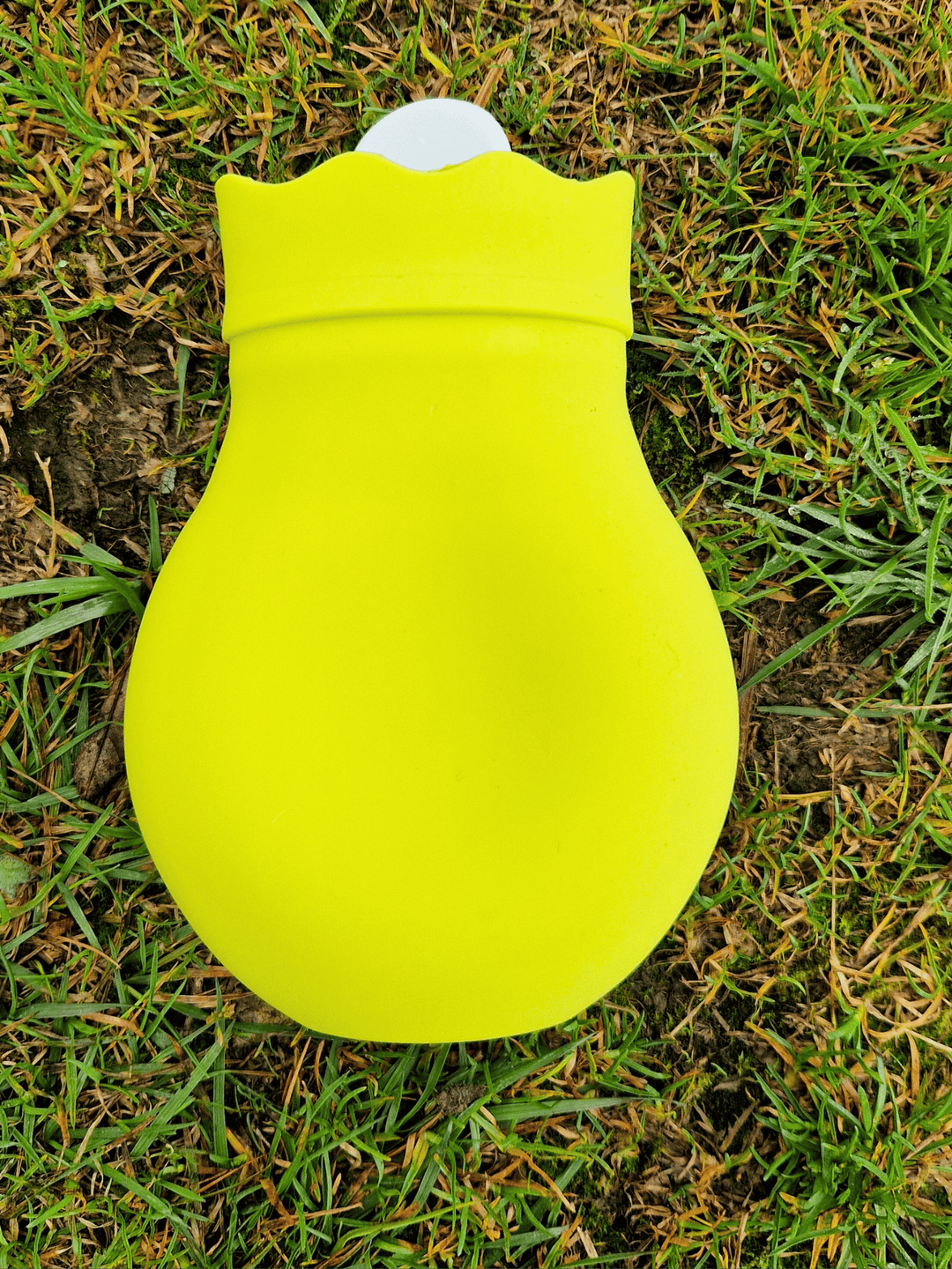 brightly coloured mini hot water bottles in lime green on a grassy surface