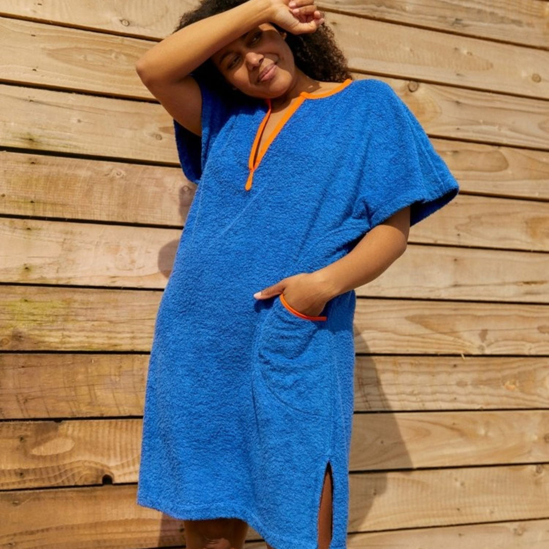 Woman wearing a So English blue beach cover up with orange trim in a soft cotton towelling material