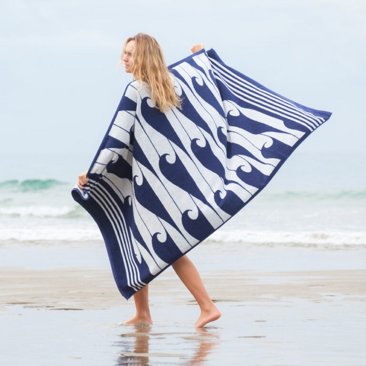 Woman holding a blue and white patterned towel on a beach