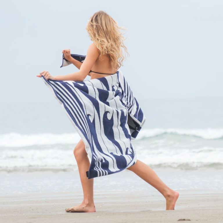 Woman on a beach holding a blue and white striped towel