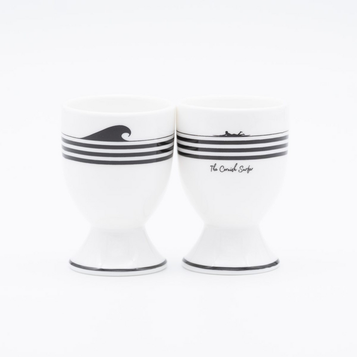 Two white ceramic egg cups with black stripes and wave design on a white background