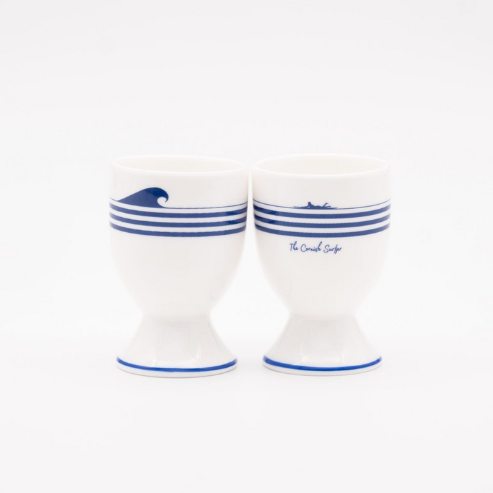 Two white ceramic egg cups with blue stripes and wave design on a white background