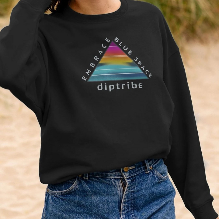 A lifestyle image of a woman wearing a diptribe black relaxed fit sweatshirt with a triangular logo and the text 'Embrace Blue Space' on the front.