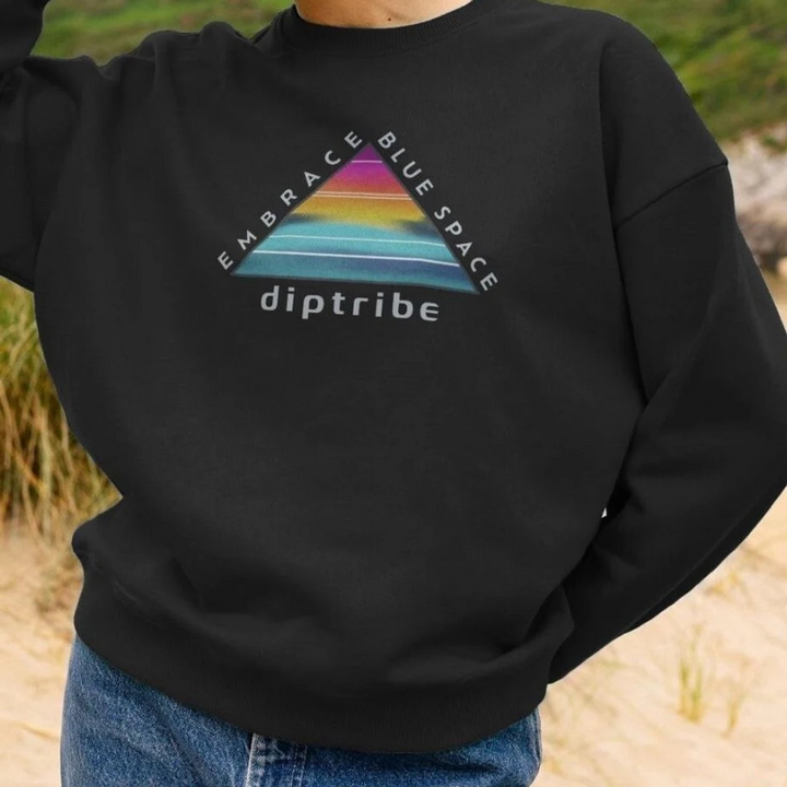 A lifestyle image of a woman wearing a diptribe black relaxed fit sweatshirt with a triangular logo and the text 'Embrace Blue Space' on the front.