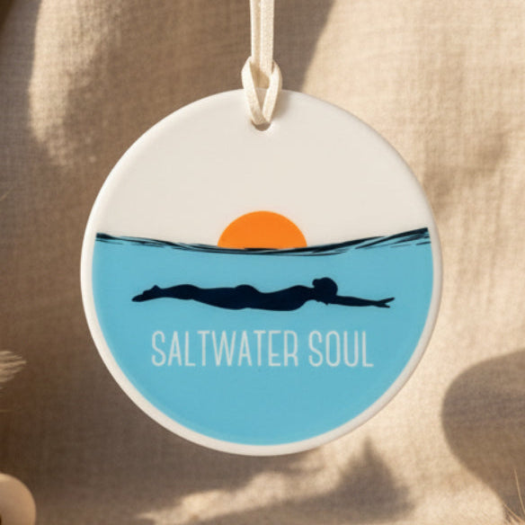 Round hanging ornament with 'Saltwater Soul' design featuring a swimmer and sunset.