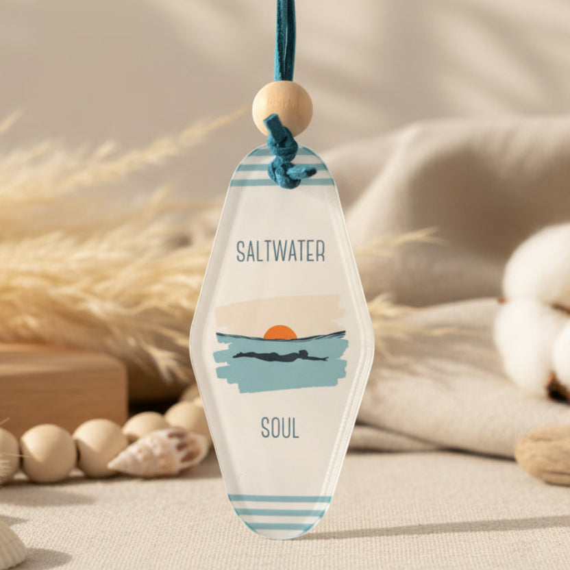 Decorative paddle with 'Saltwater Soul' text and swimmer graphic on a beige background