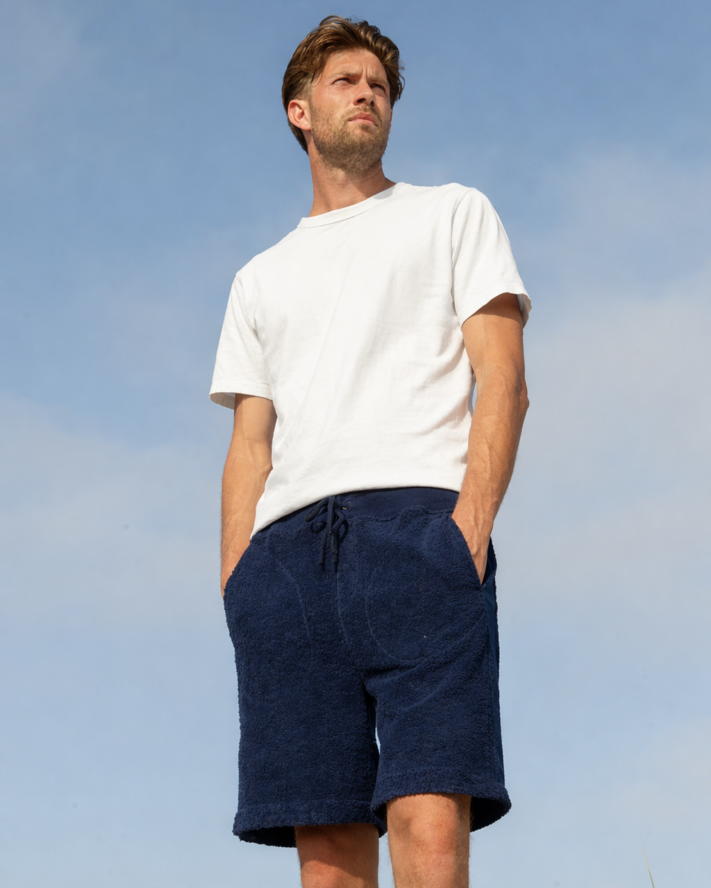 Confident man wearing navy Bear shorts by So English in casual outdoor setting, showcasing stylish beachwear made in the UK.