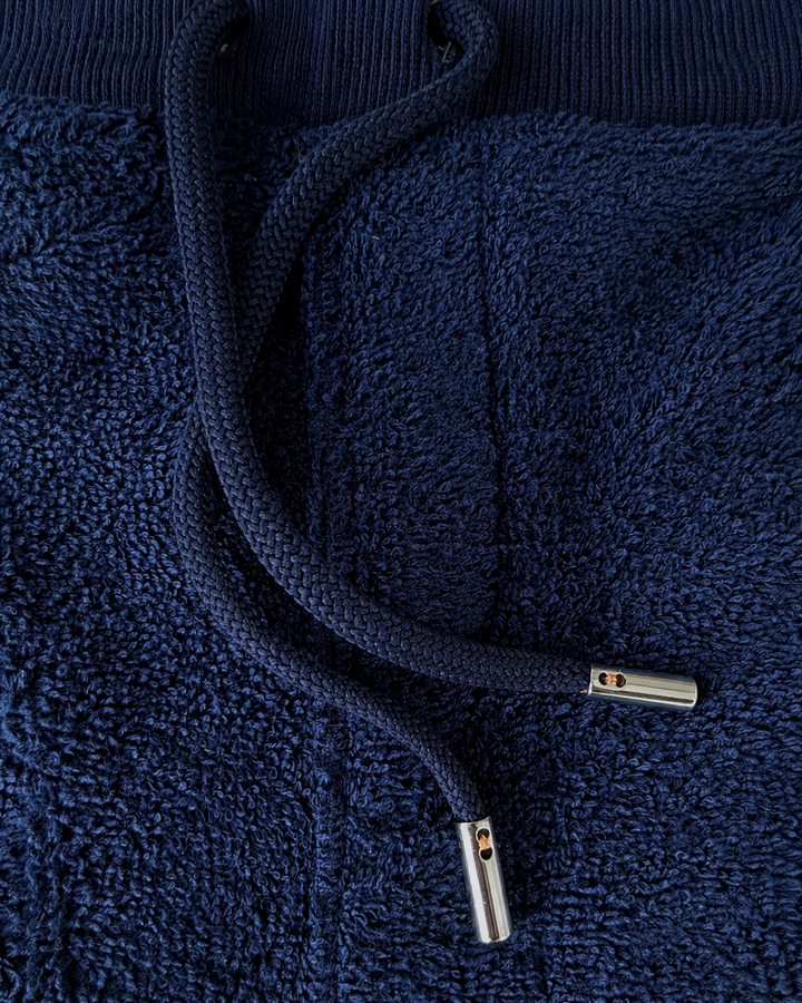 Close-up of navy blue terry cloth shorts by So English, highlighting the fabric texture and relaxed beachwear style.