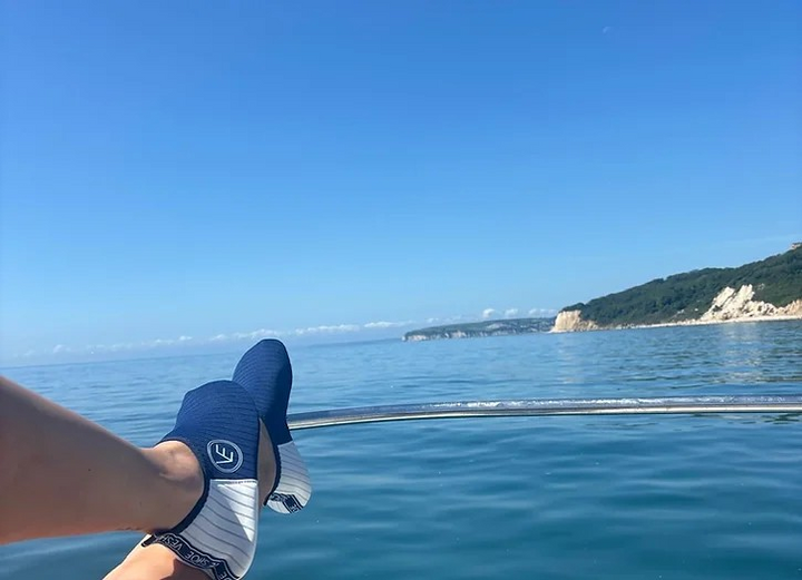Lifestyle image of a person relaxing on a boat wearing the VE Shoe navy and white water shoes with white soles
