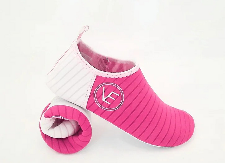 Flat shot of a pair of VE Shoe hot pink water shoes with a white sole. 