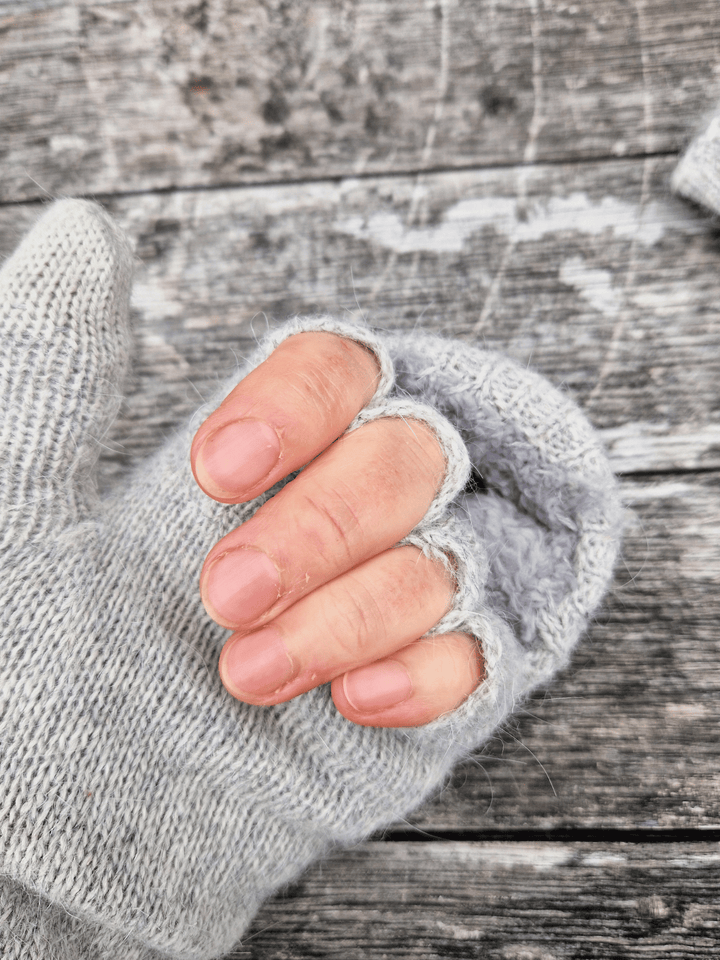 Close-up of a hand wearing a grey fingerless glove on a wooden surface