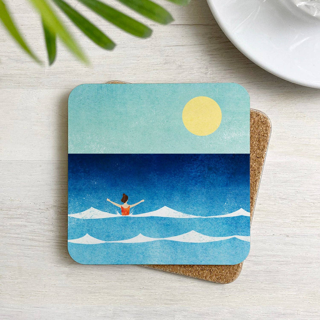 Dip in the Sea cork-backed coaster with an illustration by Henry Rivers displayed on a table in a home setting.