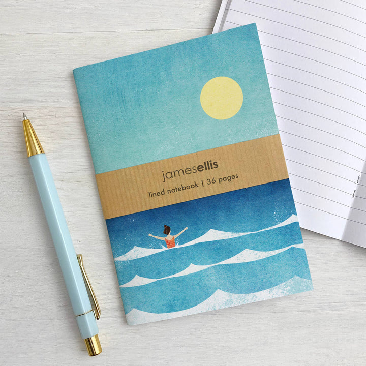 Dip in the Sea A6 notebook by Henry Rivers displayed beside an open notebook and pen.