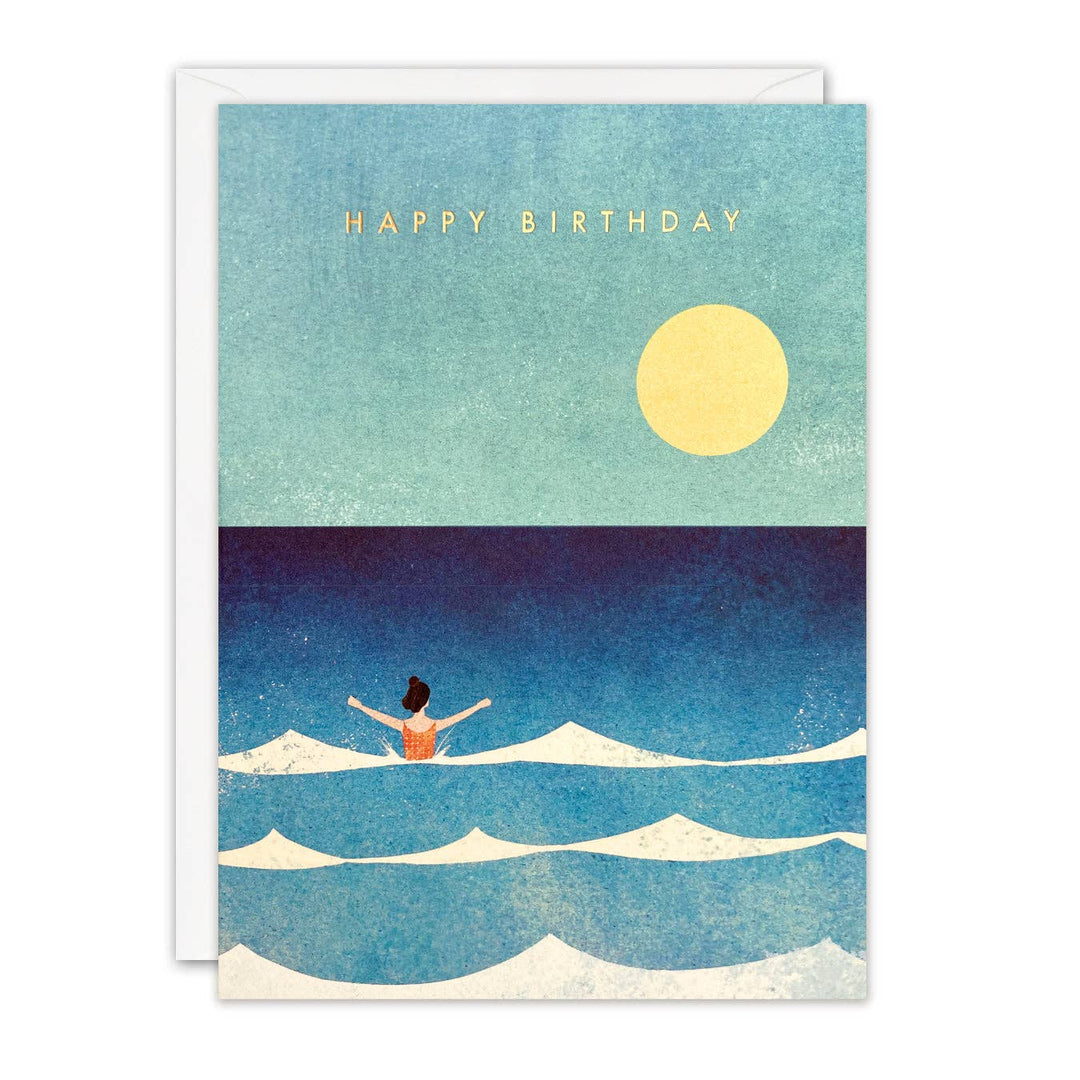 Dip in the Sea wild swimming birthday card illustrated by Henry Rivers featuring a lone swimmer beneath a golden sun with Happy Birthday in gold foil.