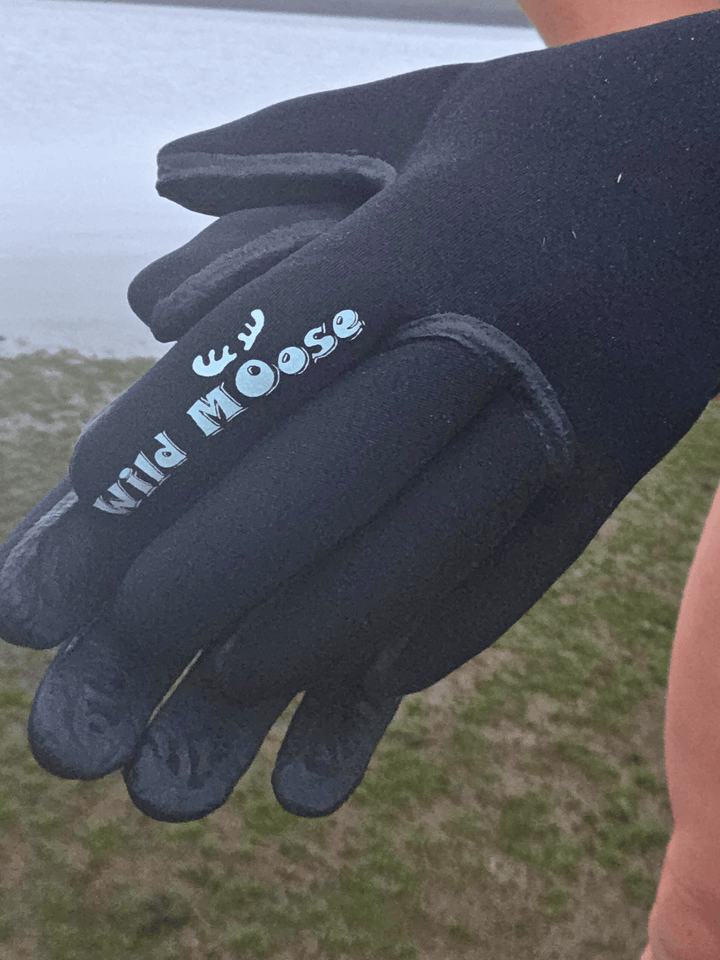 Black glove with 'Wild Moose' branding held in front of a blurred natural background