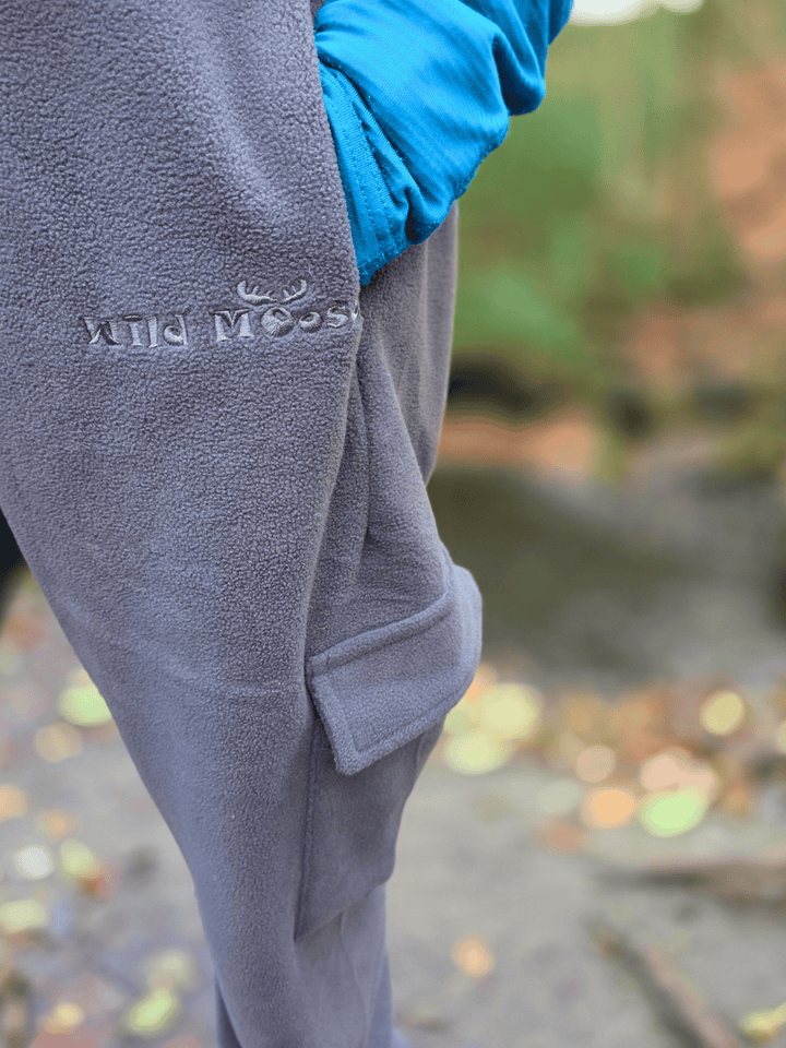 Gray fleece jogging pants with a Wild Moose brand logo on a blurred natural background