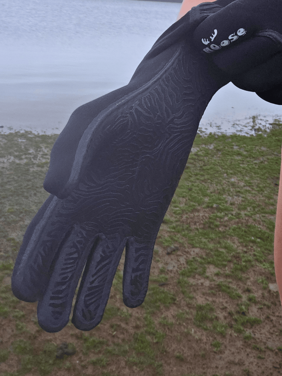 Black glove with textured palm against a natural background