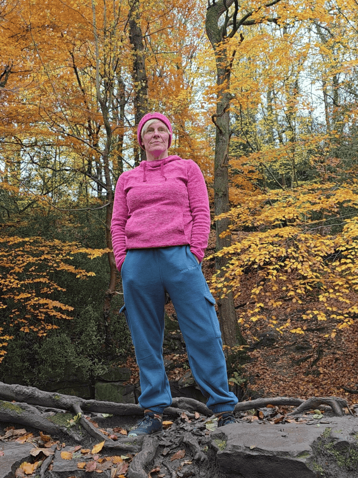 Person in petrol blue fleece jogging pants standing on a log in an autumn forest