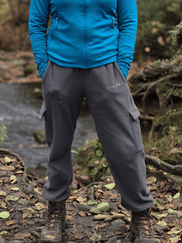 Person wearing grey fleece jogging pants standing in a forest setting.