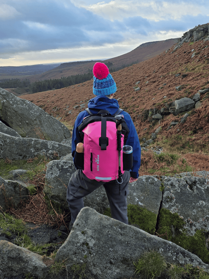 Person hiking in a mountainous area with a pink backpack
