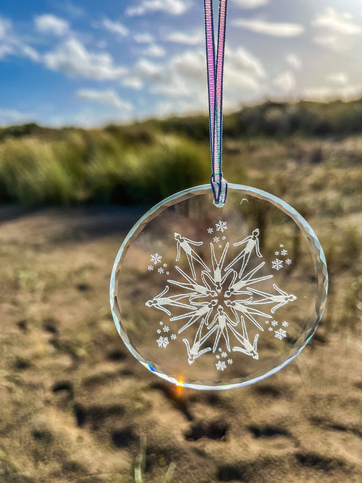 Glass snowflake decoration featuring synchronized swimmers, hanging on ribbon – festive gift for open water swimmers.