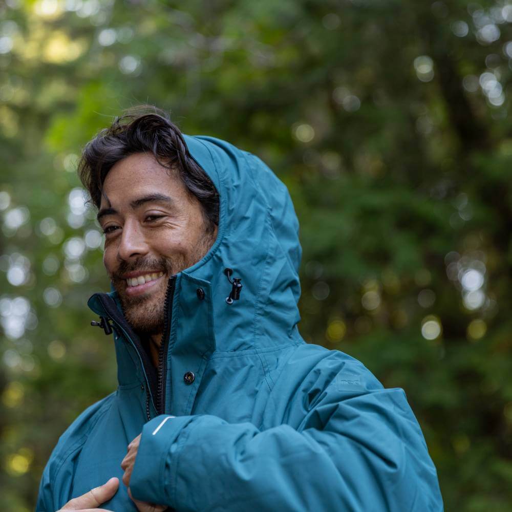Lifestyle image of man wearing a Red Alter Evo long sleeve waterproof changing robe in Deep Teal.