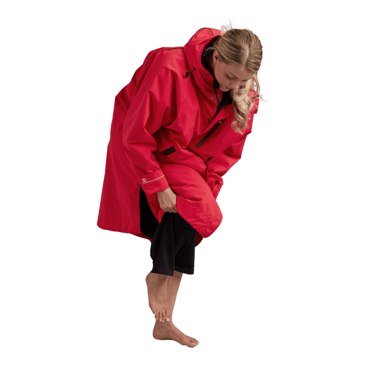 Side profile of a woman changing underneath the Red Alter Evo long sleeve waterproof changing robe in Siren Red.