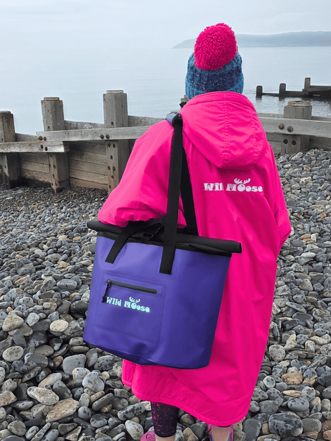 Person wearing a pink robe and holding a purple tote bag with &